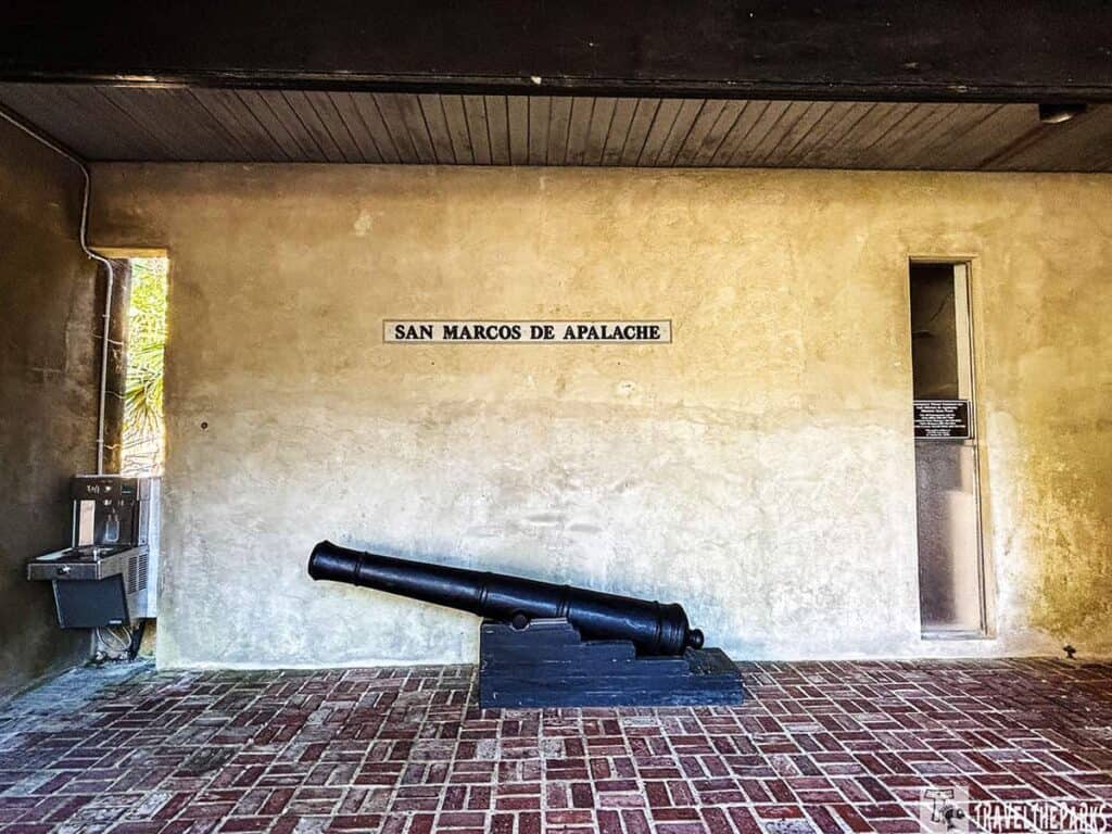Interior view of a historic fort showing a cannon and a sign reading "San Marcos de Apalache."