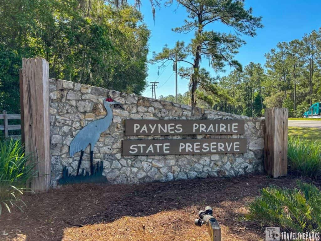 Entrance sign for Paynes Prairie State Preserve with a stone base and wooden planks displaying the park's name.