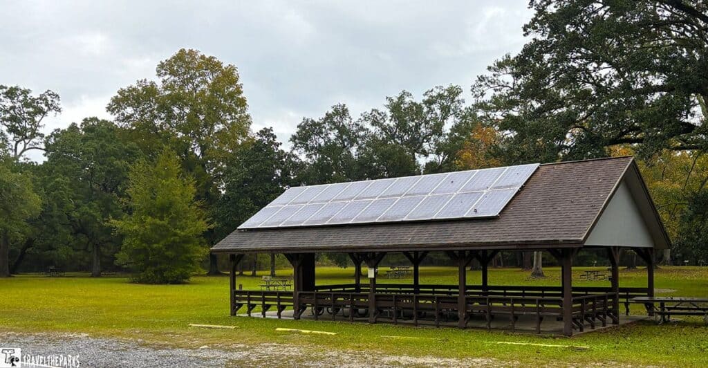 Picnic area with a pavilion equipped with solar panels at Gulf Islands National Seashore’s Davis Bayou, surrounded by trees.