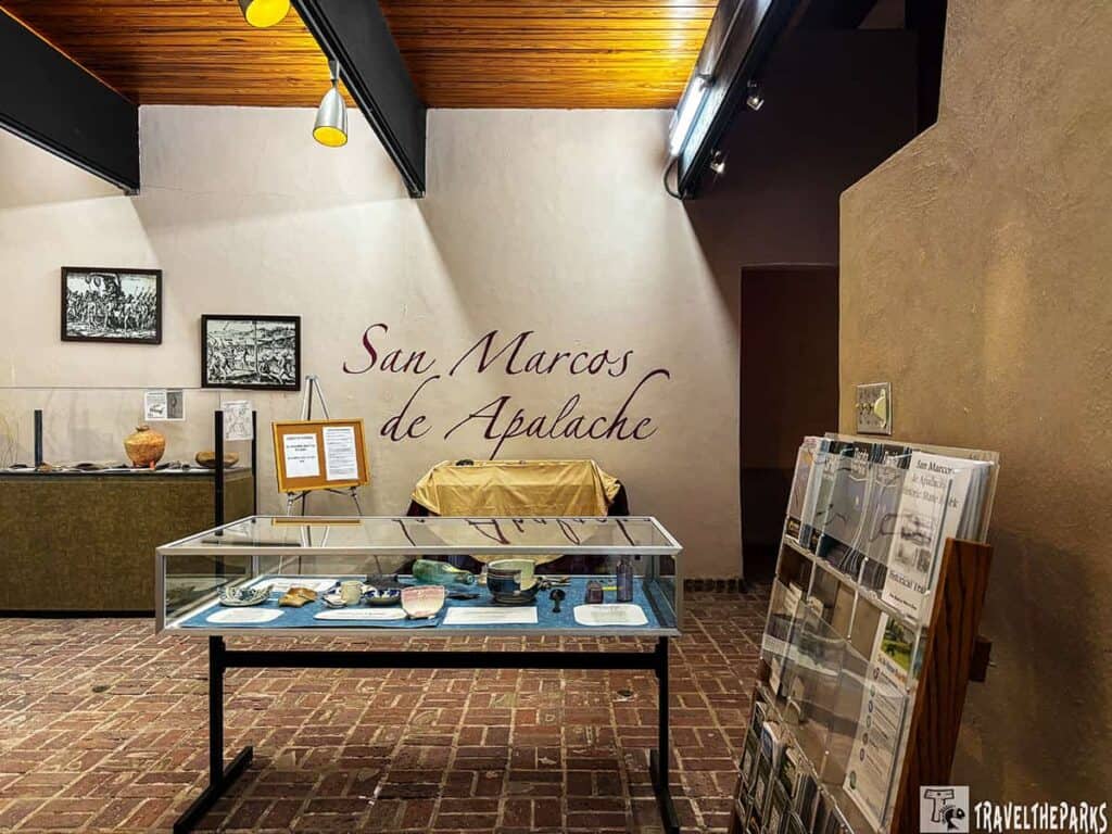 Interior view of Fort San Marcos de Apalache Museum with displays, framed art, and brochures.