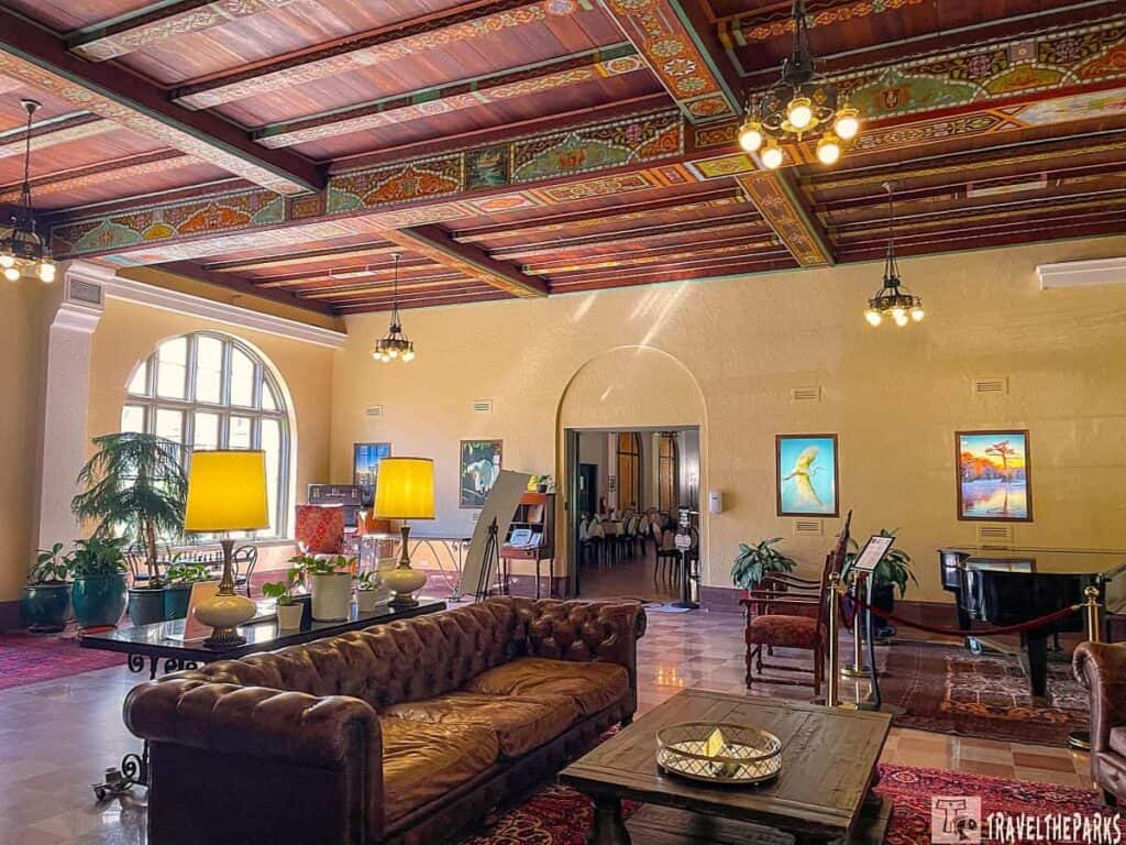 Interior of Wakulla Springs Lodge with a leather sofa, ornate ceiling, and grand piano.