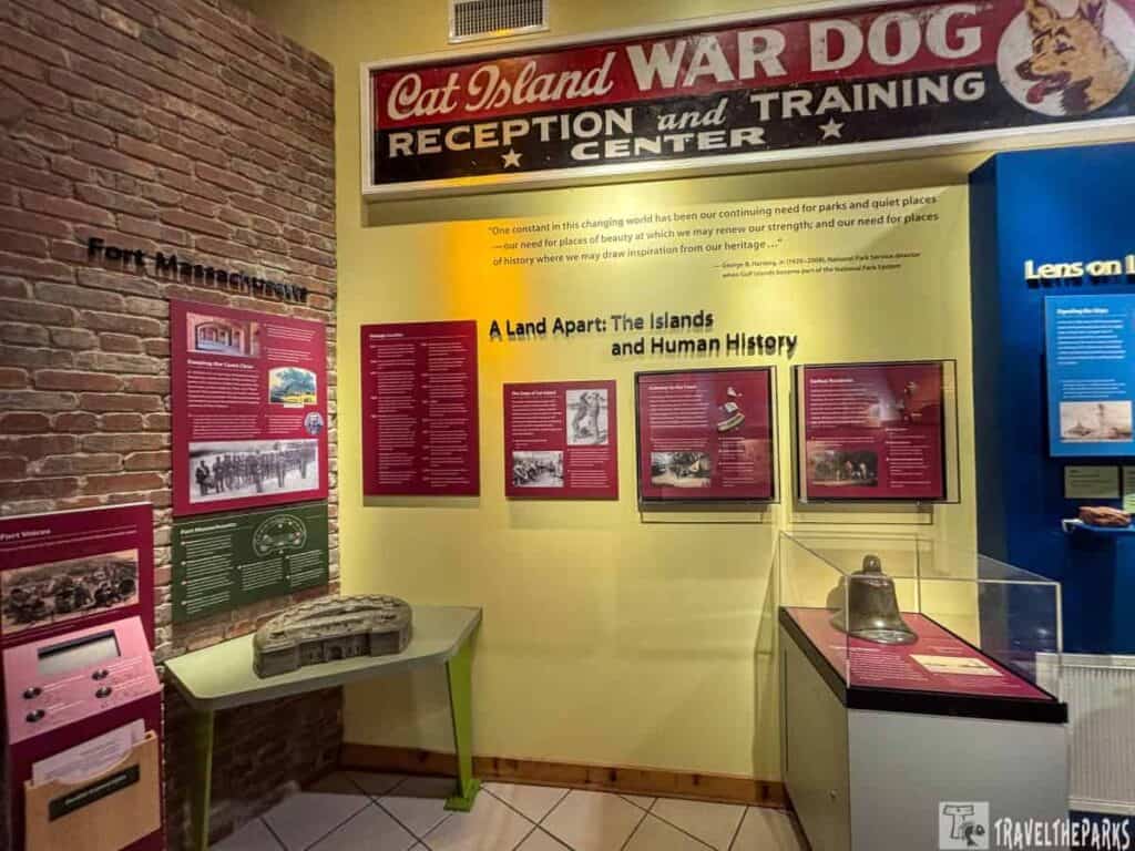 Museum display featuring Cat Island War Dog Center sign, Fort Massachusetts exhibits, and historical panels.
