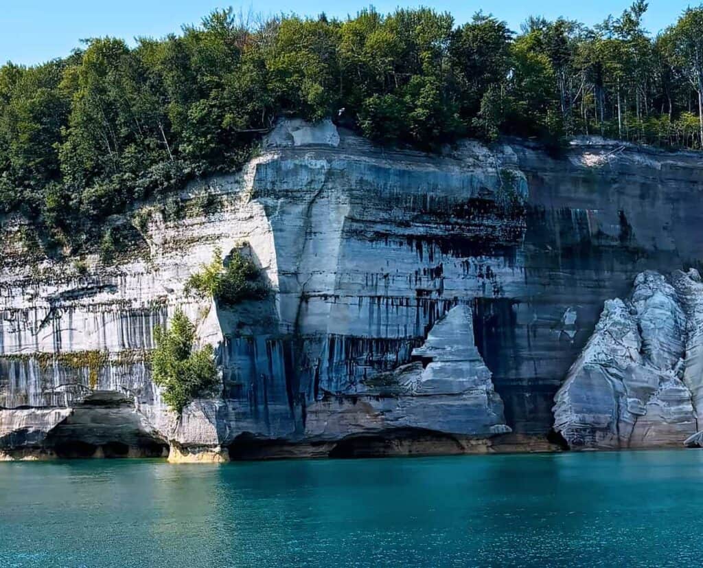 Cliffs at Pictured Rocks National Lakeshore with layered rock, caves, and turquoise water below.
