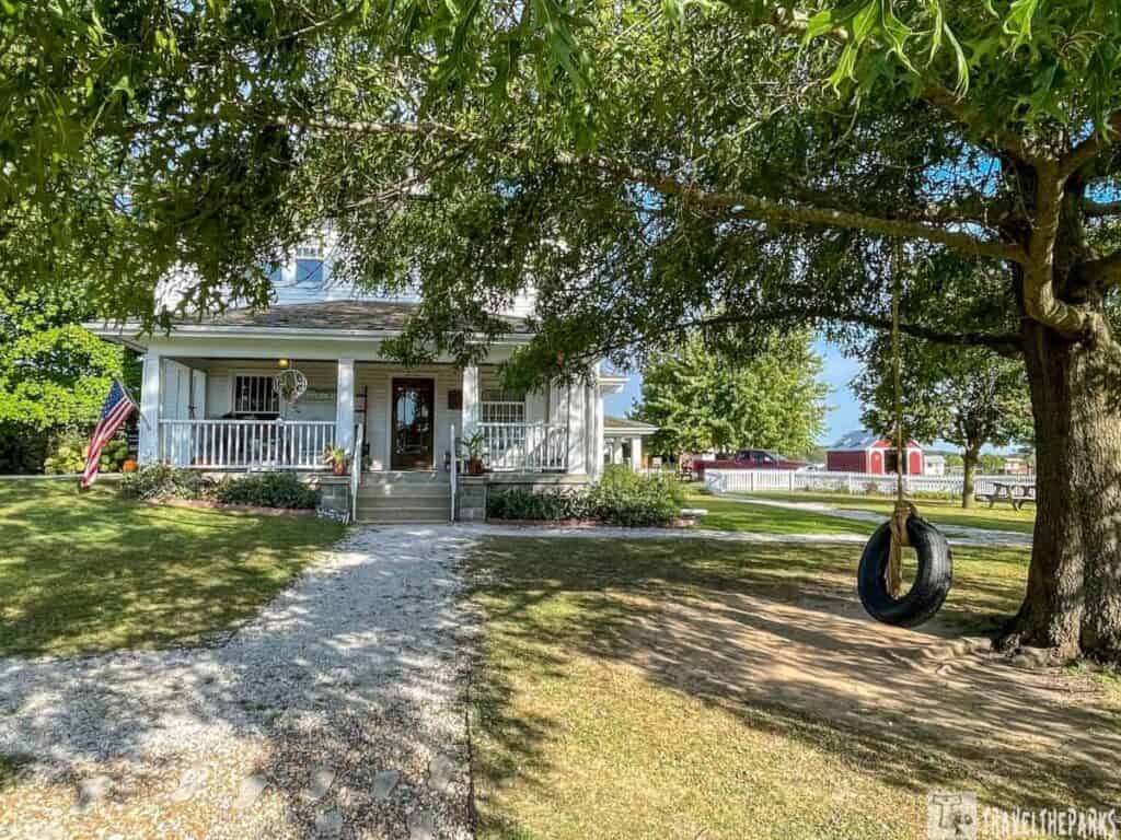 A white farmhouse with a porch and tire swing at Prophetstown State Park.