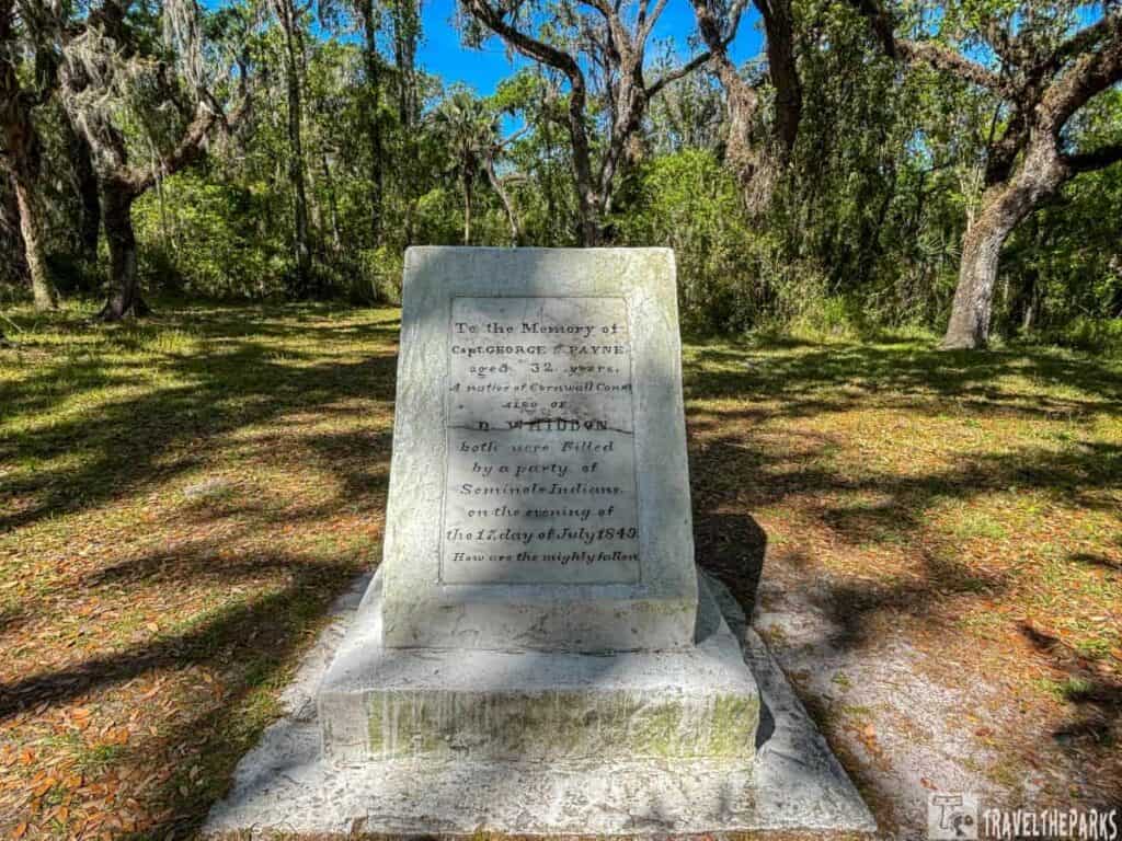 A stone monument in a shady forest clearing.