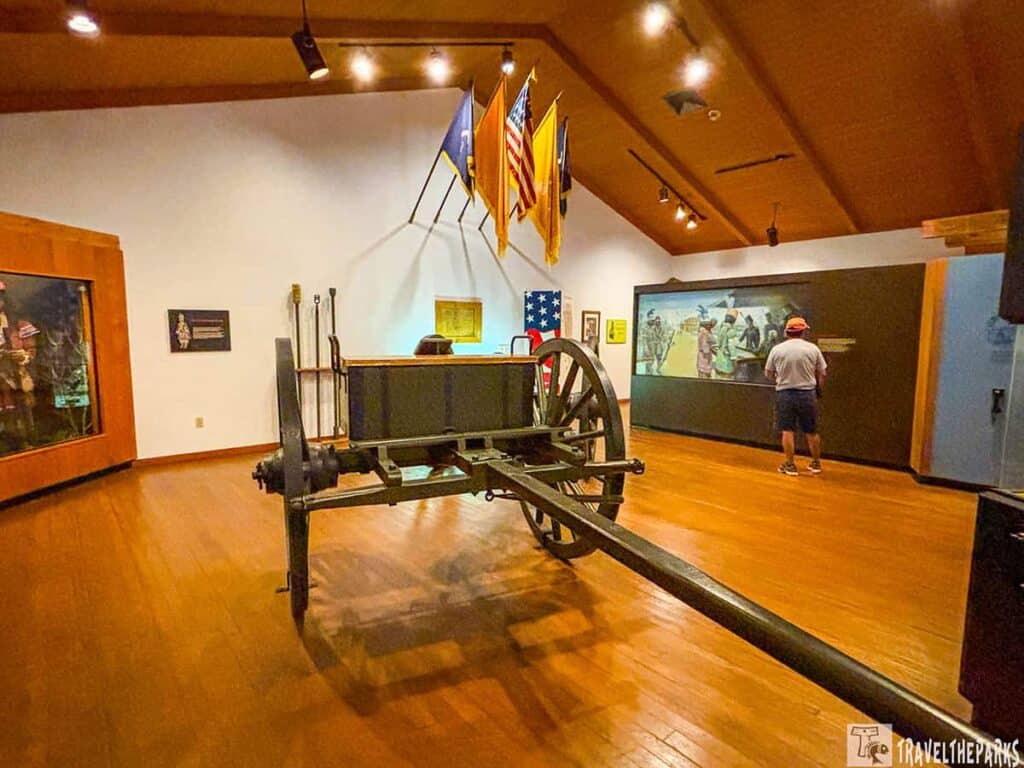 Museum exhibit at Paynes Creek State Historic Park featuring a cannon carriage, display case, and informational mural.