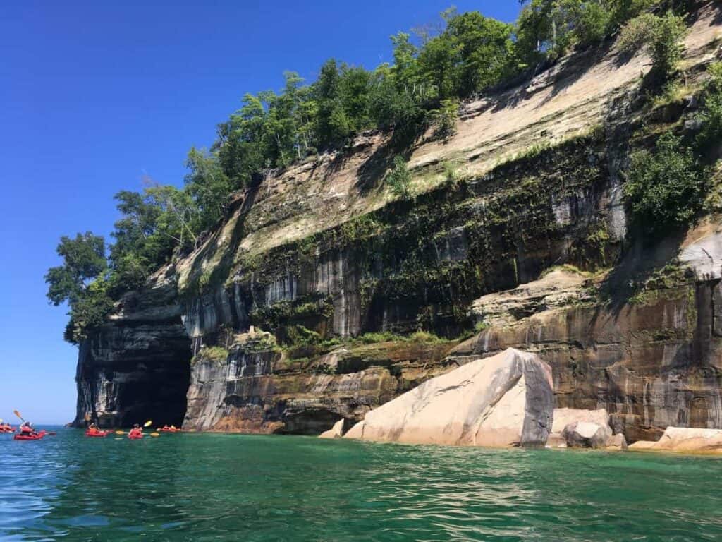 Kayakers paddling on Lake Superior along the colorful mineral stained cliffs of Pictured Rocks. NPS Photo