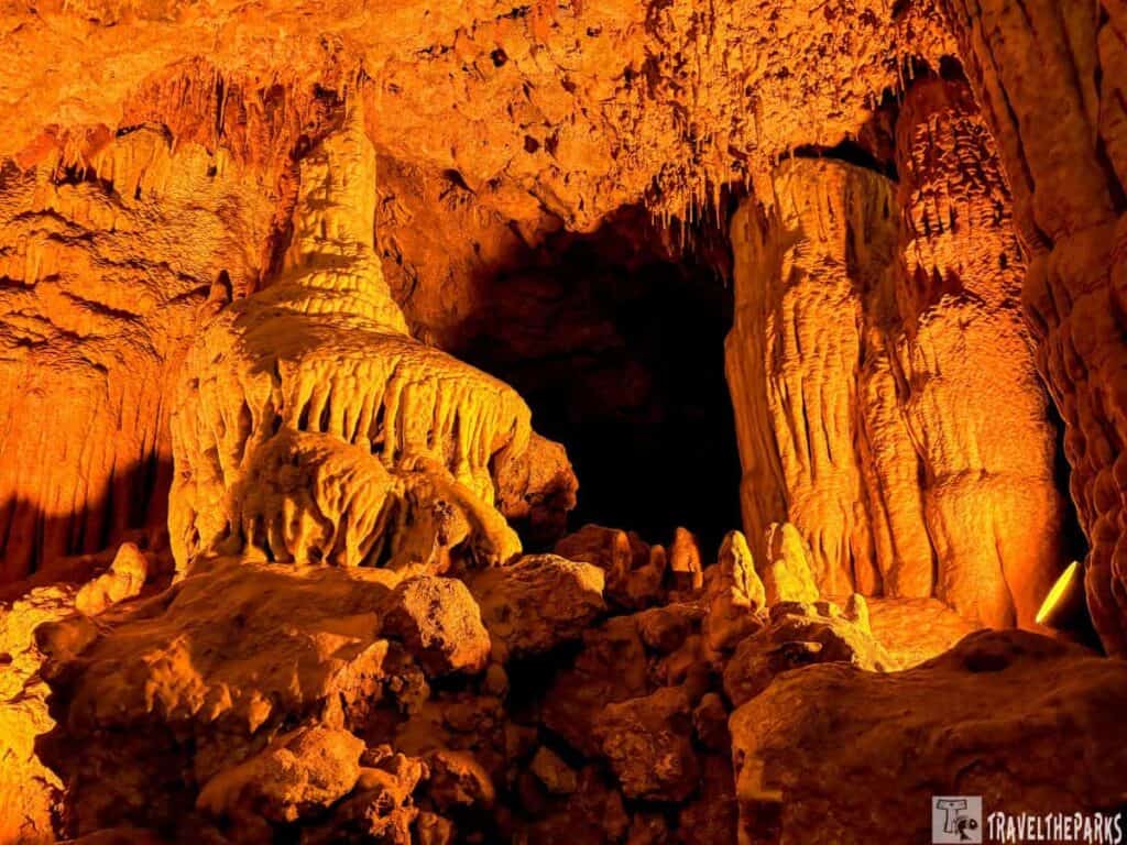 A view of stalactites inside a cave at Florida Caverns State Park, featuring warm orange lighting that accentuates their textures.

