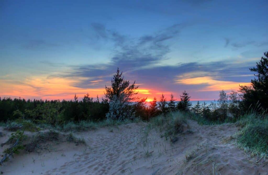Sunset over sandy dunes and trees at Pictured Rocks National Lakeshore.