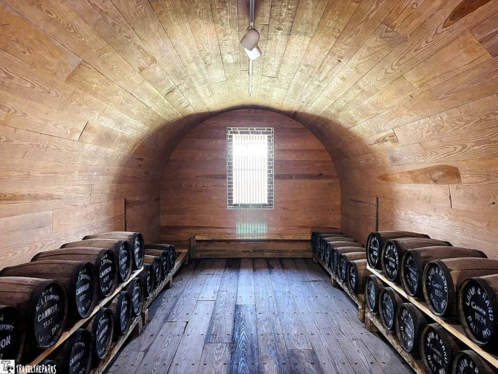 A wooden room with stacked barrels on each side and a small window at the end.