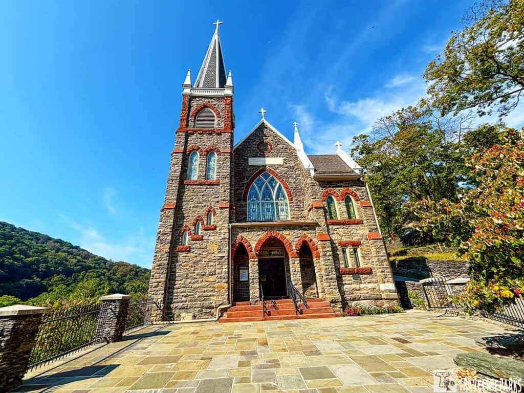 St. Peter's Catholic Church with Gothic architecture in Harpers Ferry, featuring a stone facade and red brick accents under a blue sky.