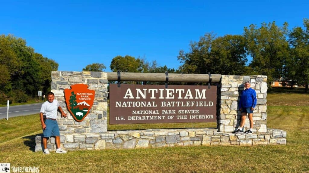 Antietam National Battlefield stone entrance sign with two people standing on either side.