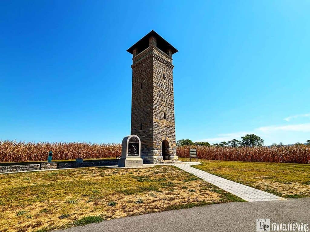 Stone observation tower at Antietam National Battlefield, with a memorial in front and a cornfield in the background under a blue sky.