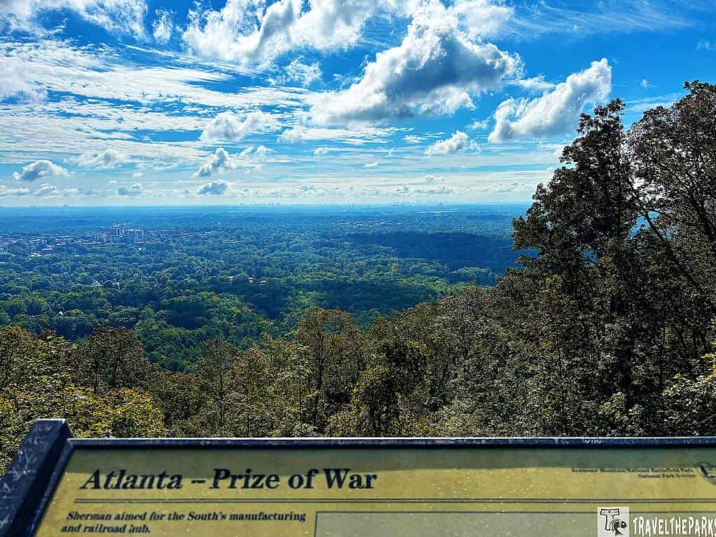 A scenic view from Kennesaw Mountain National Battlefield Park with Atlanta's skyline in the distance under a blue, cloud-filled sky.