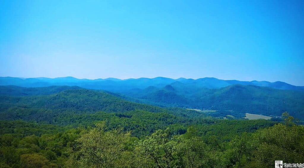 Scenic view of lush green hills and distant blue mountain ranges under a clear blue sky at Black Mountain Rock State Park.