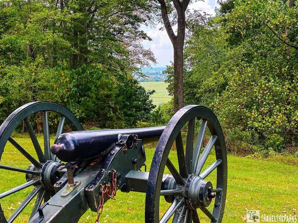 A historical cannon on Bolivar Heights overlooking trees and a distant landscape.

