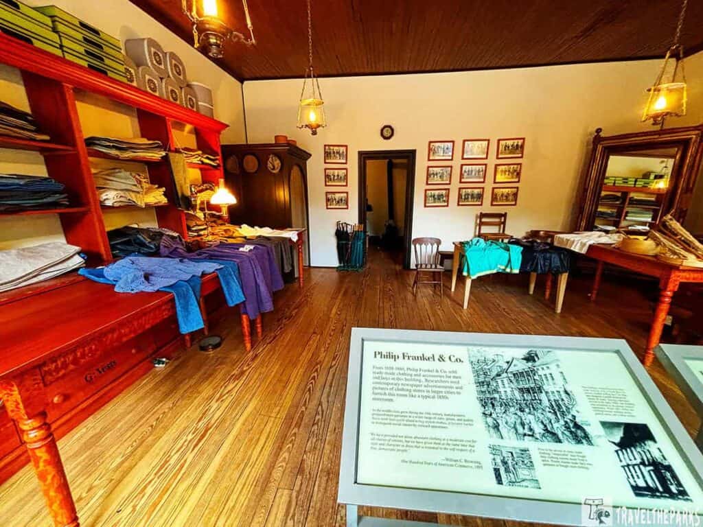 Interior of a historical fabric shop with wooden furnishings, fabric displays, and informational signage.