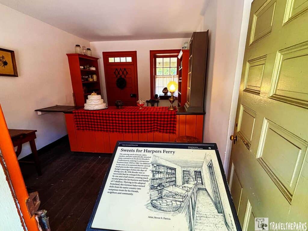 Interior of a small confectionery with a wooden counter, decorative cake, and vintage lamp.