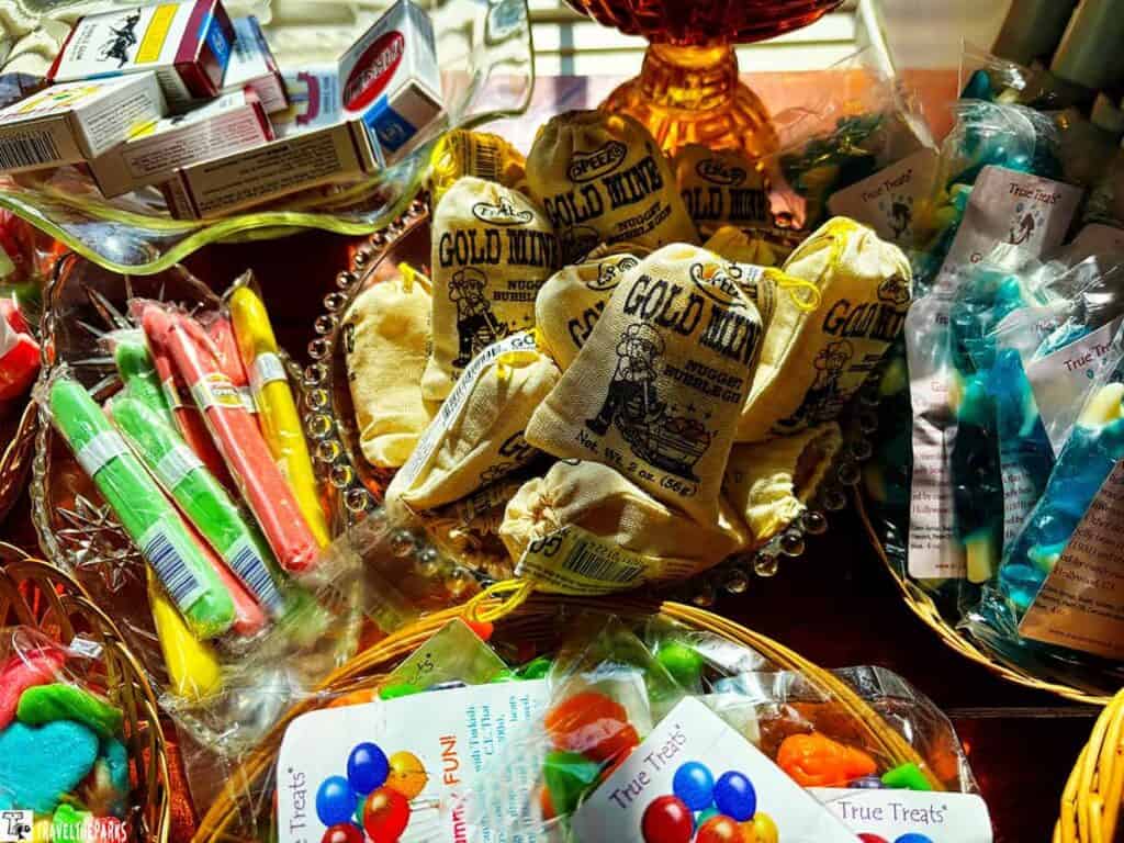 A variety of vintage-themed candies, including Gold Mine Nugget Bubble Gum bags and colorful candy sticks.