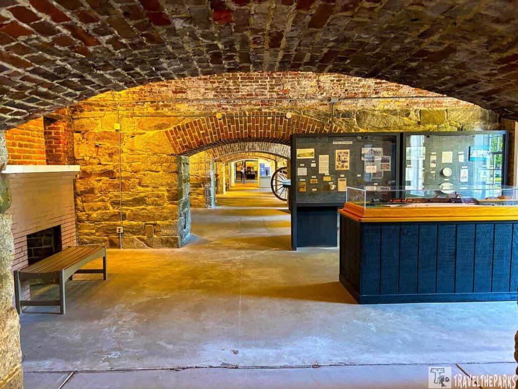 Arched stone hallway with brick ceiling and display case in Fort Monroe.