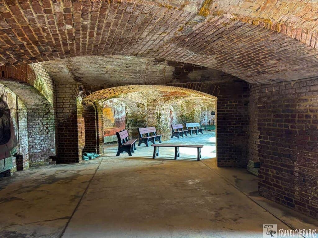 Interior view of Fort Sumter National Monument with arched brick corridors and wooden benches.