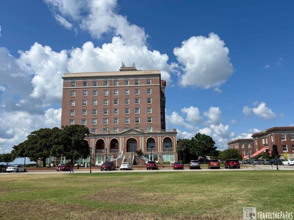 Chamberlin Hotel in Hampton, Virginia, with a brick facade and arched entrances, set against a blue sky with clouds.

