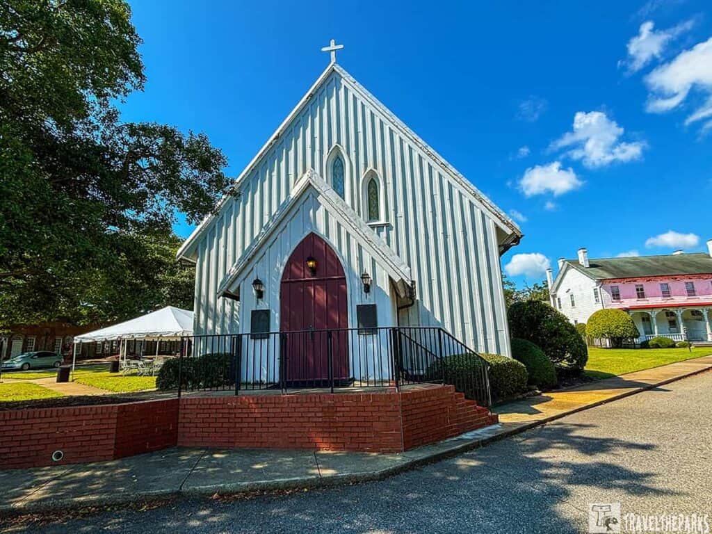 Chapel of the Centurion at Fort Monroe with a steep roof and maroon door under a blue sky.