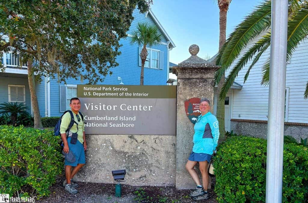 Two people stand by a Cumberland Island National Seashore Visitor Center sign.
