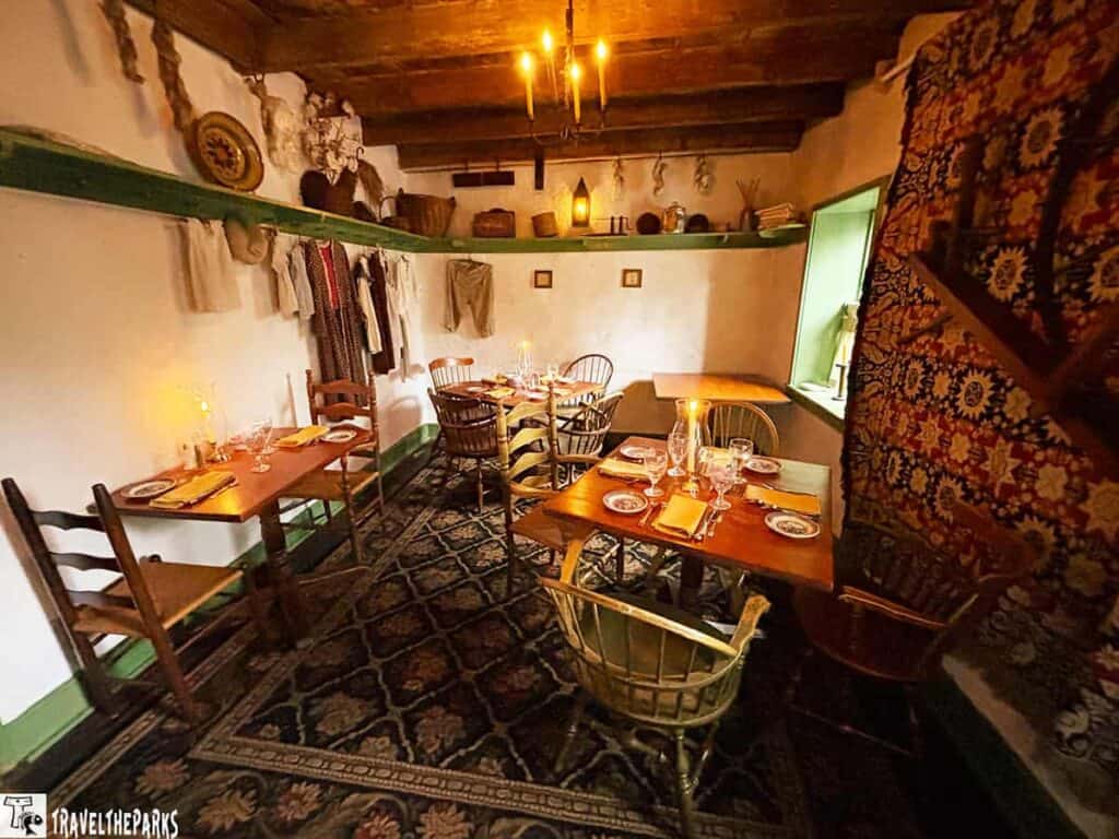 A historic Dobbins Tavern dining room with wooden tables and chairs, decorated with rustic shelves and candles.