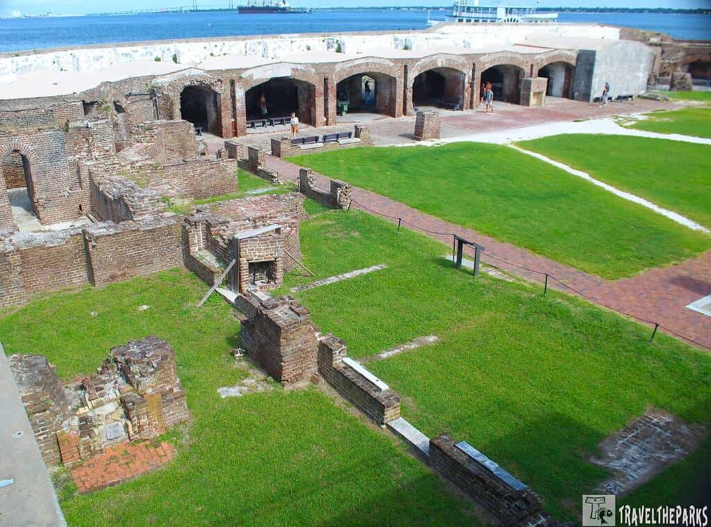 View of brick ruins and grassy areas at Fort Sumter National Monument with arched brick structures and waterfront in the background.