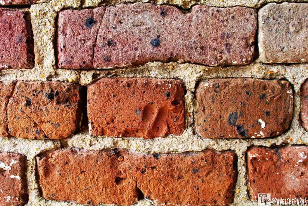 Close-up of a brick wall with varied reddish-brown bricks and visible fingerprint impression.