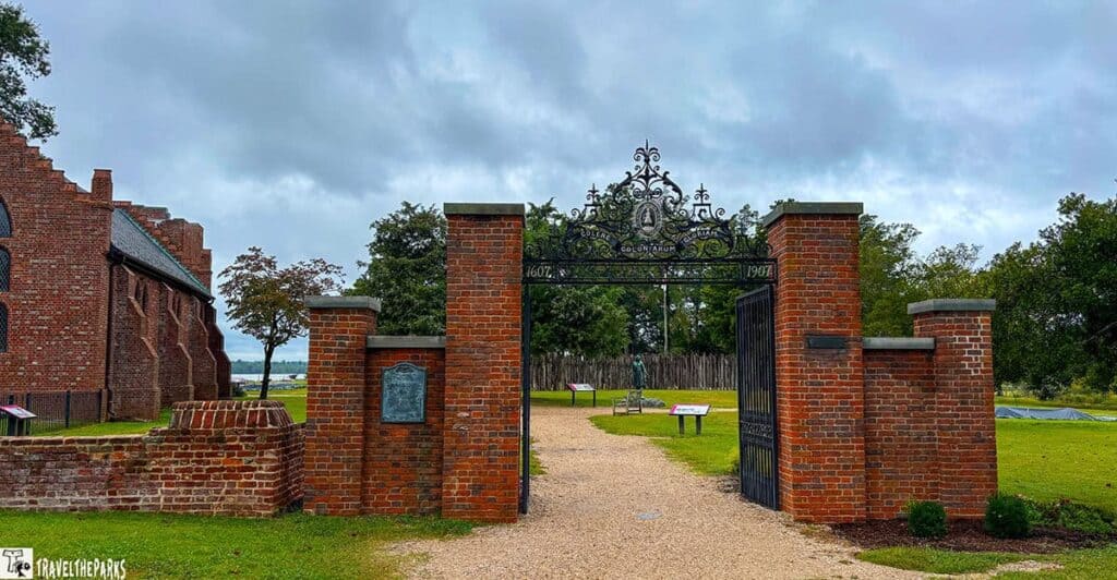 Entrance to James Fort at Jamestown's Old Town, featuring red brick pillars and a wrought iron arch.