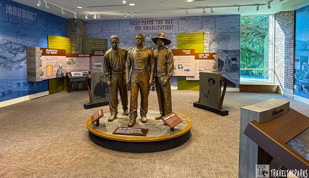 Exhibit room with three bronze statues and historical panels on emancipation.