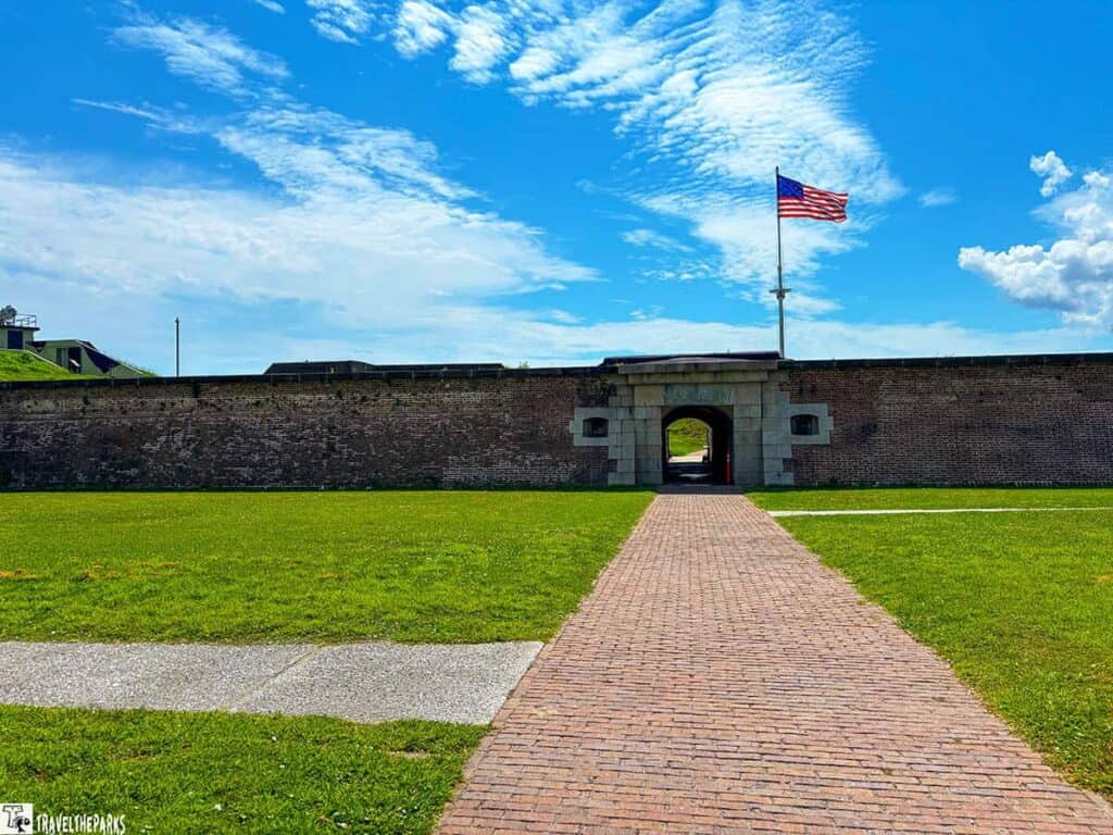 Fort Moultrie entrance with a brick pathway leading to an archway, and an American flag flying above.