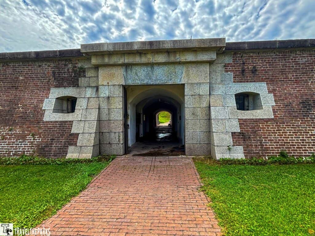 Entrance of historical Fort Moultrie National Monument with an arched doorway and cloudy sky above.