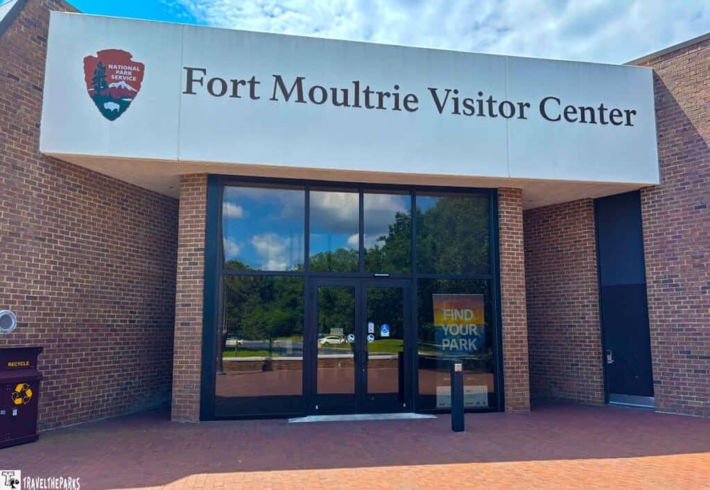 Entrance to Fort Moultrie Visitor Center with a glass facade and brick walls.