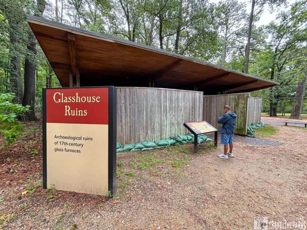 Glasshouse Ruins at Historic Jamestowne with a wooden structure and visitor reading a sign.