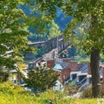 View of Harpers Ferry with a bridge over a river, framed by trees and surrounded by brick buildings.