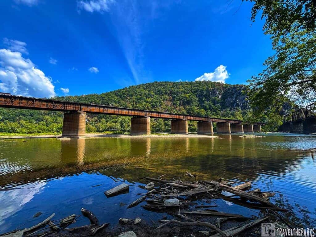 Railroad bridge over a river with a wooded hill in the background at Harpers Ferry.