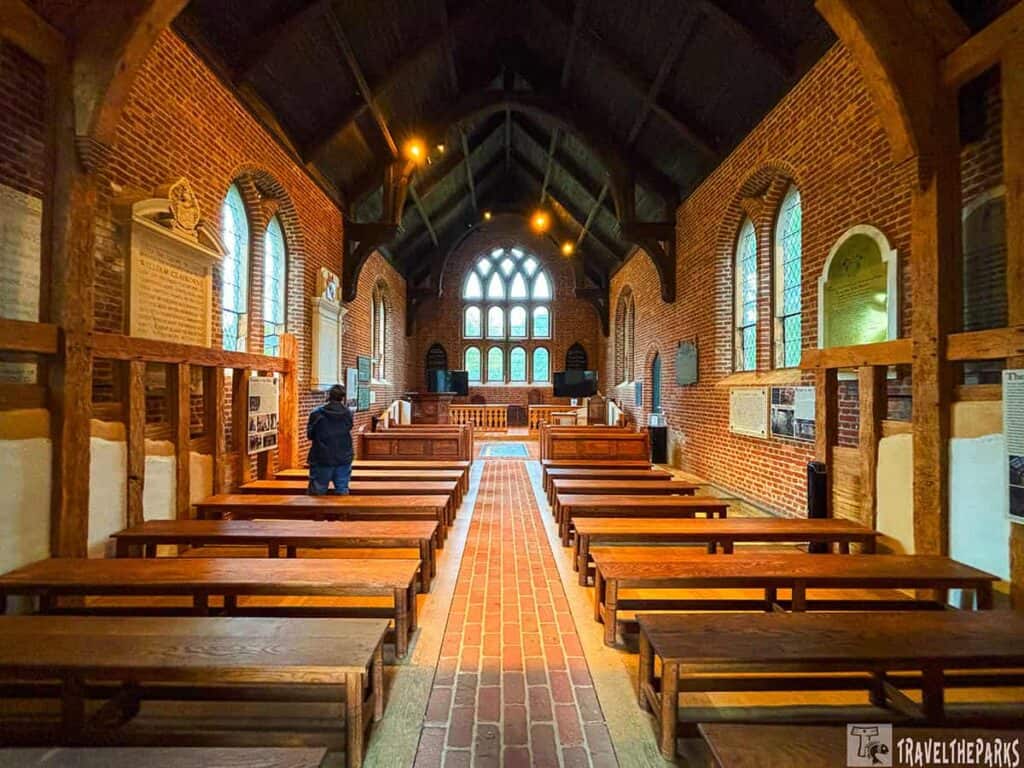 Interior of the 1907 Memorial Church at Historic Jamestowne with brick walls, wooden pews, and arched stained glass windows.