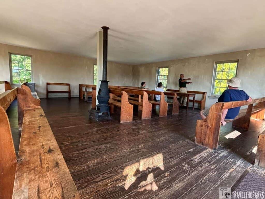Interior of Dunker Church at Antietam with wooden pews and a central cast iron stove.