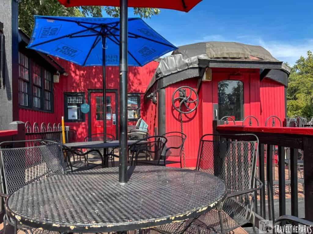 Restaurant outdoor patio with red building and blue umbrella.