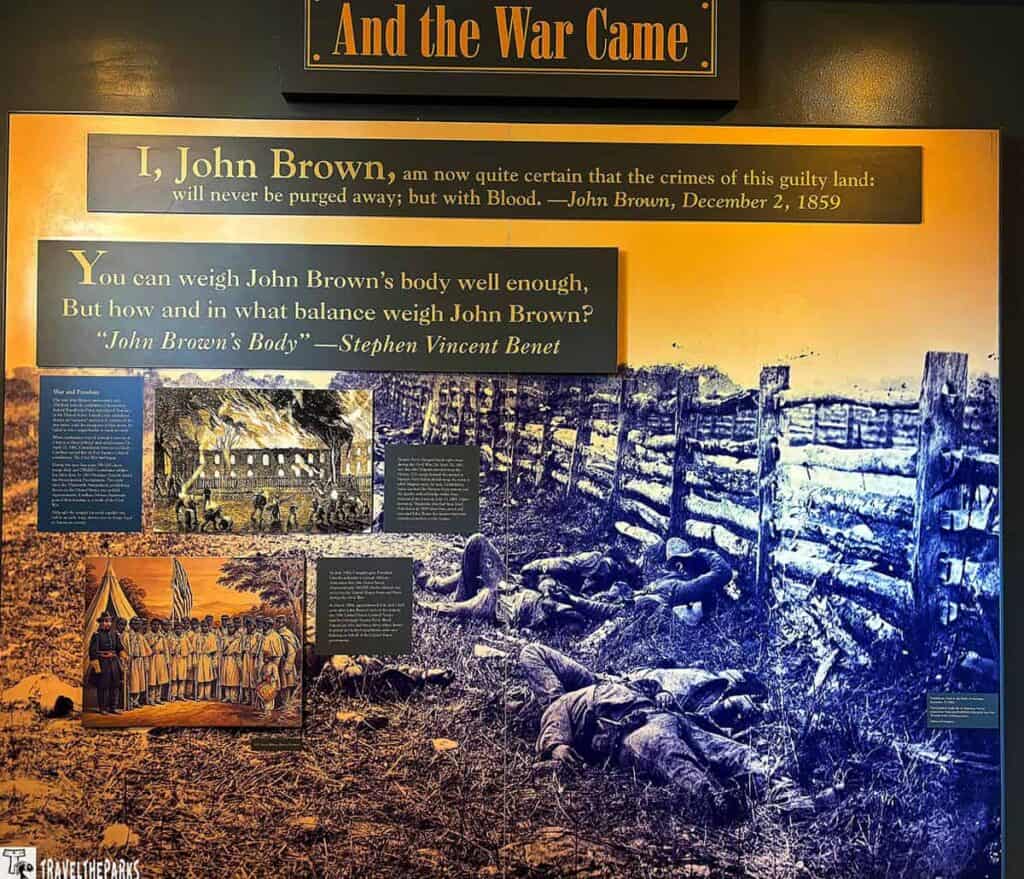 Exhibit display featuring quotes about John Brown, historical images of a battlefield, a burning building, and a group of men with flags.


