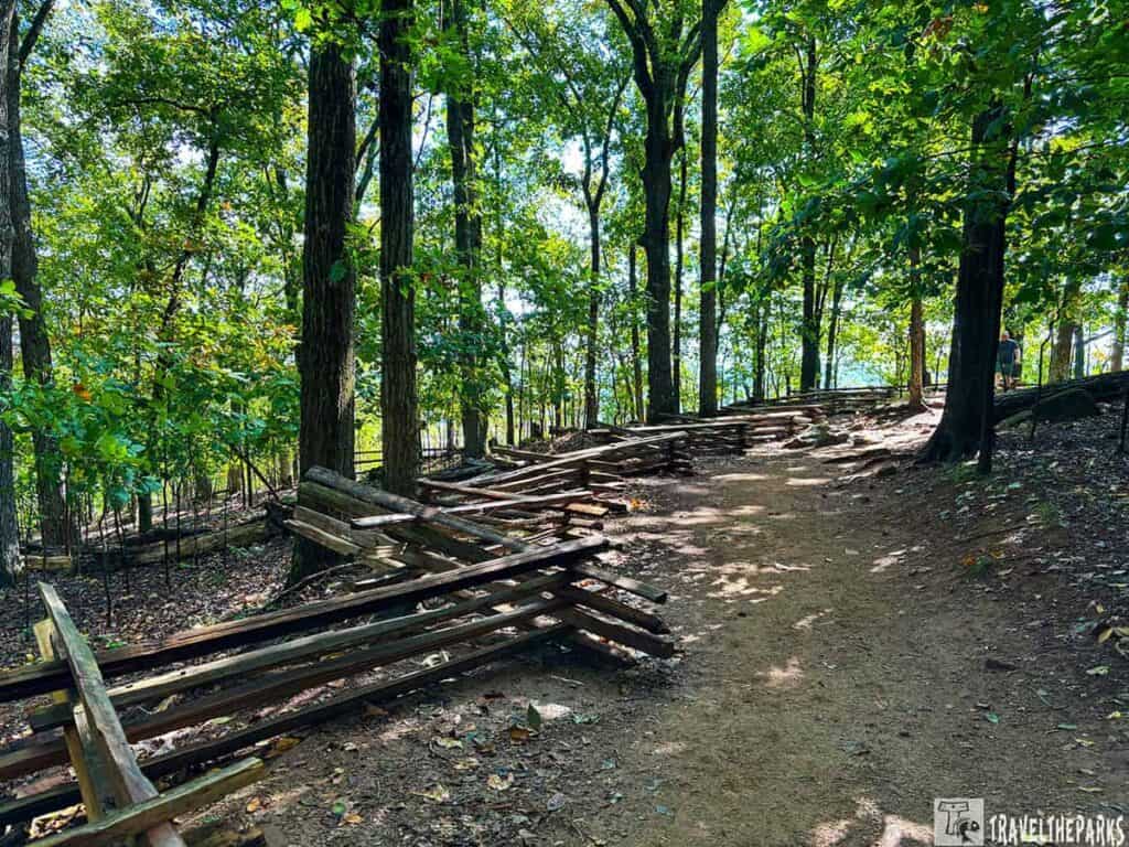 A dirt path through a forest at Kennesaw Mountain National Battlefield Park, bordered by a wooden zigzag fence.