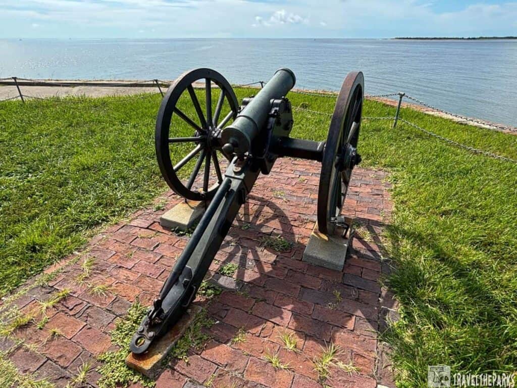 Mountain howitzer on a grassy hill at Fort Sumter with water in the background.