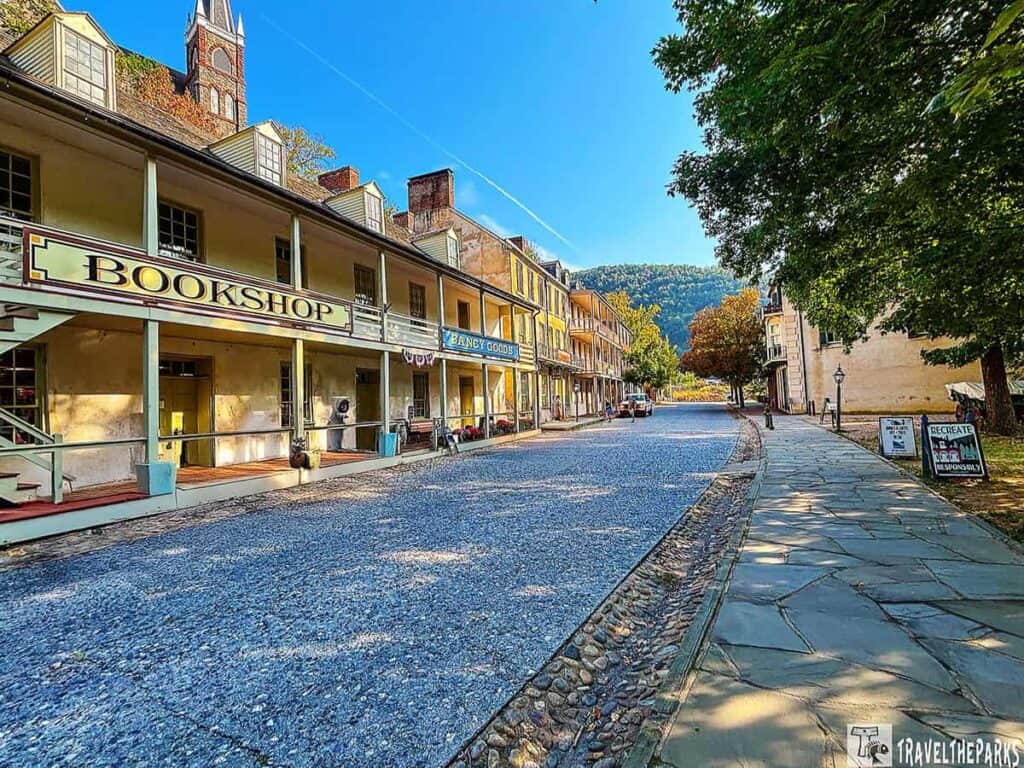 Street view of historic buildings in Harpers Ferry NHP with a bookshop sign and cobbled street.