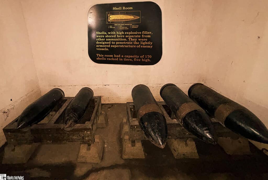 A room with large black artillery shells on wooden racks, and a plaque with information about the "Shell Room."

