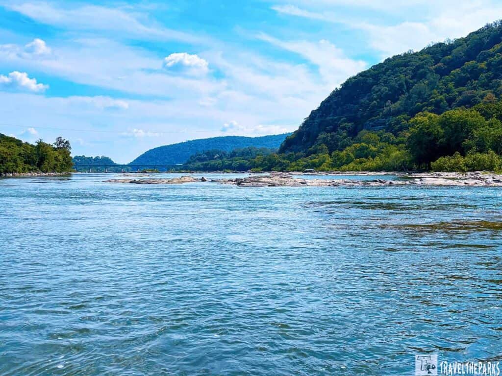 Scenic view of the Shenandoah River at Harpers Ferry with a small bridge in the distance.
