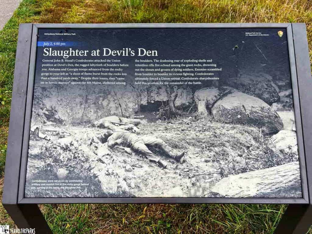 Informational plaque at Gettysburg detailing the Battle at Devil’s Den with a historical photo of fallen soldiers.
