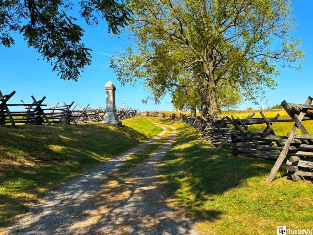 Sunken road with wooden fences and a stone monument at Antietam National Battlefield.
